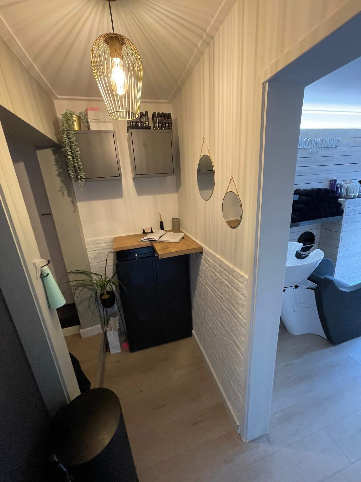 Entree van de salon met een warme hanglamp en ronde spiegels